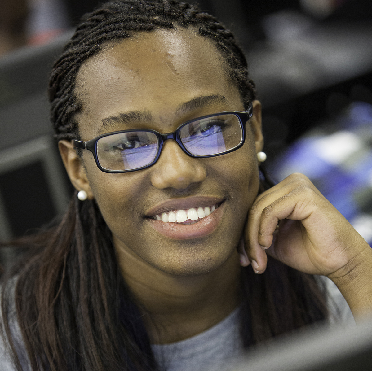 Student smiling at camera, while sitting in front of a computer