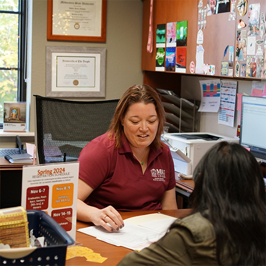 An academic advisor in Dillard College happily works with a student to prepare for the next semester.