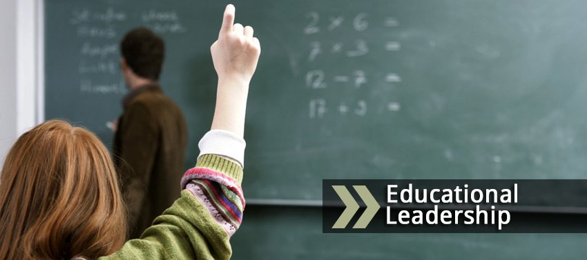 Educational Leadership image showing a student in class raising her hand as the professor writes on the board.