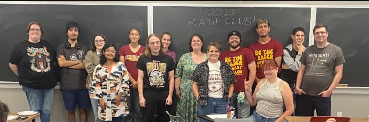 2025 Math club students standing in front of a chalk board that has 2025 Math Club written on it.
