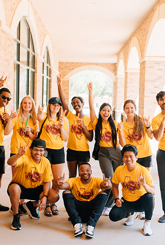 A group of MSU Texas students who work in admissions pose together, smiling, outside of Legacy Hall.