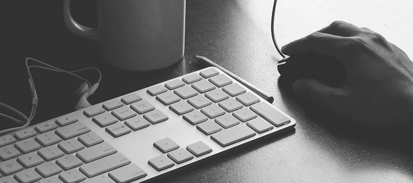 Hand on mouse next to keyboard.