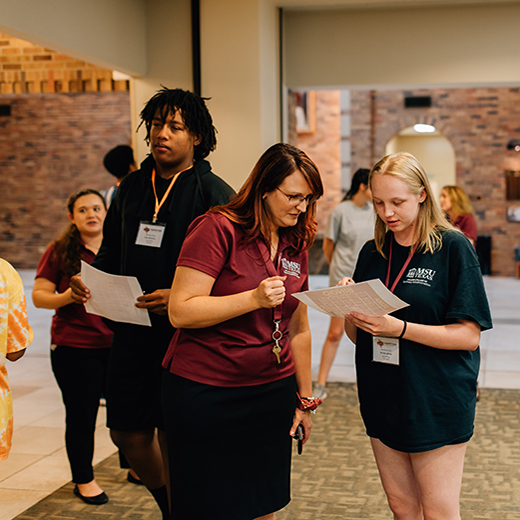 A group of students and MSU Texas employees are gathered, chatting inside the Dillard College of Business Administration during an event.