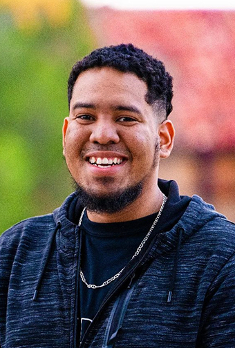 A student happily smiles for the camera while walking around campus.