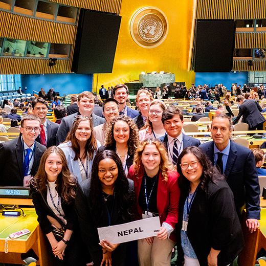 A group of smiling students gathered together with their professor at the Model United Nations event, representing the country of Nepal.