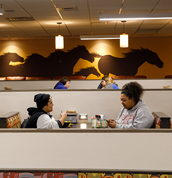 Two students sitting together in the dining hall.
