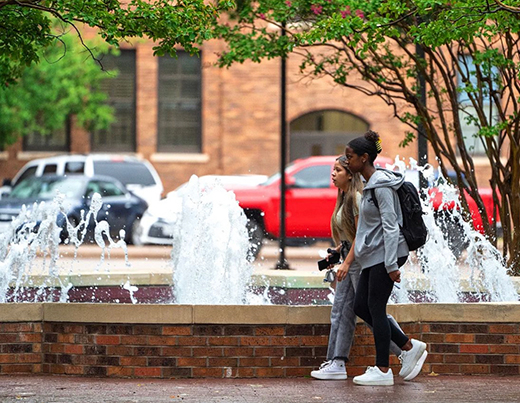 Two students walking past Bolin Fountain in the quad.