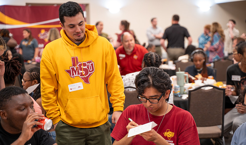 Three students are gathered at a table during the Rising Sophomore Summit