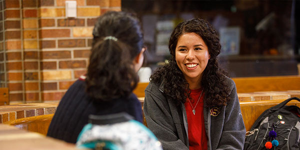 Two students conversing in library.