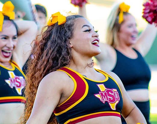 MSU Texas cheerleaders engage with the crowd as they happily cheer.